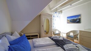 A bedroom with a bed, a dresser, a chair, a mirror, and a painting on the wall. - Apartment with balcony directly on the banks and with a view of the Moselle (Bullay)