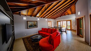 Un salón amplio con un sofá seccional rojo, un televisor de pantalla plana y un comedor con sillas y una mesa.