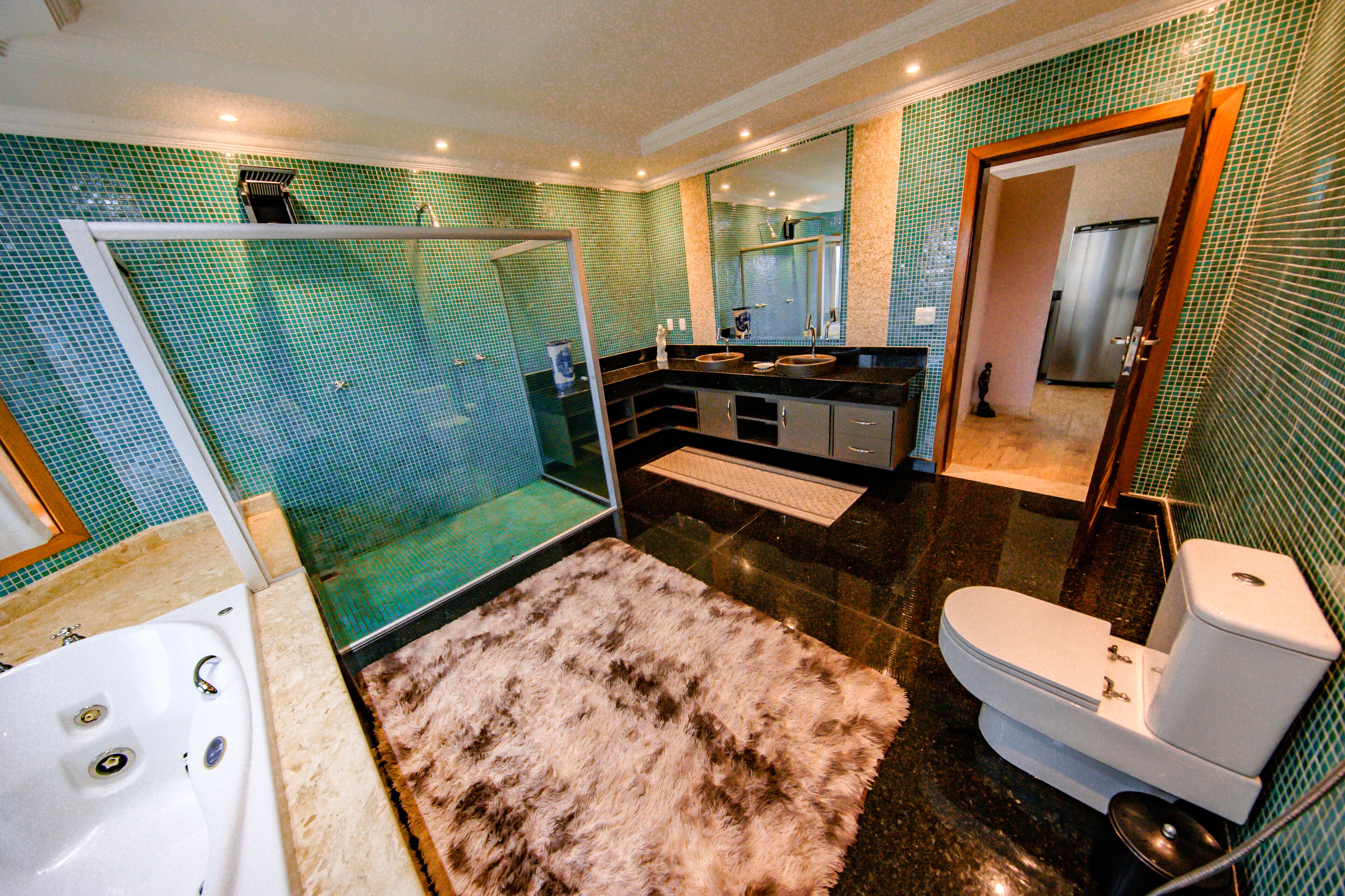 A modern bathroom with a glass-enclosed shower, a fluffy rug, a white toilet, and a sink with a mirror above it.