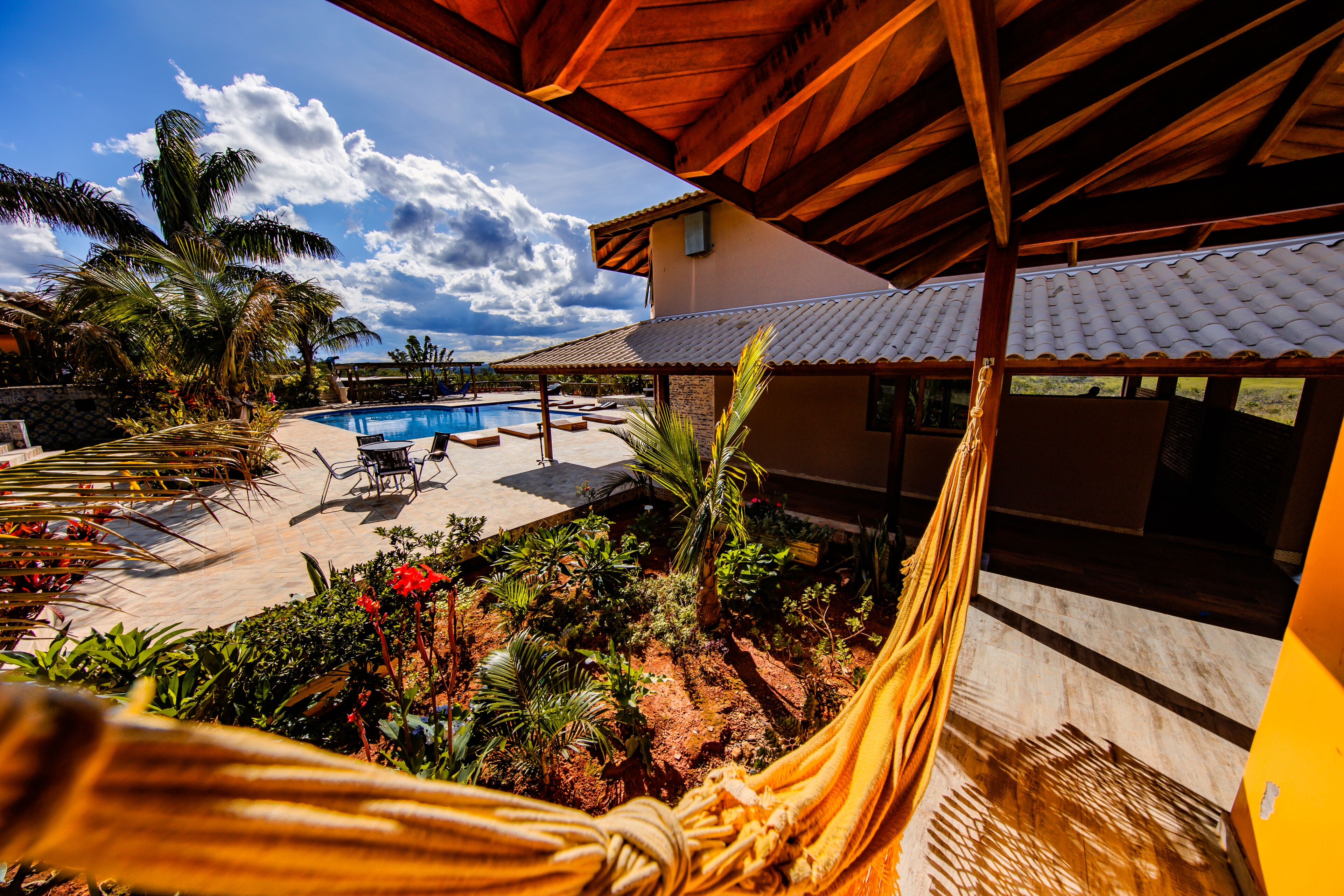A pool area with a hammock, palm trees, and a covered patio.