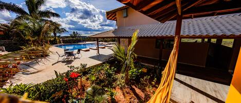 A pool area with a hammock, palm trees, and a covered patio.