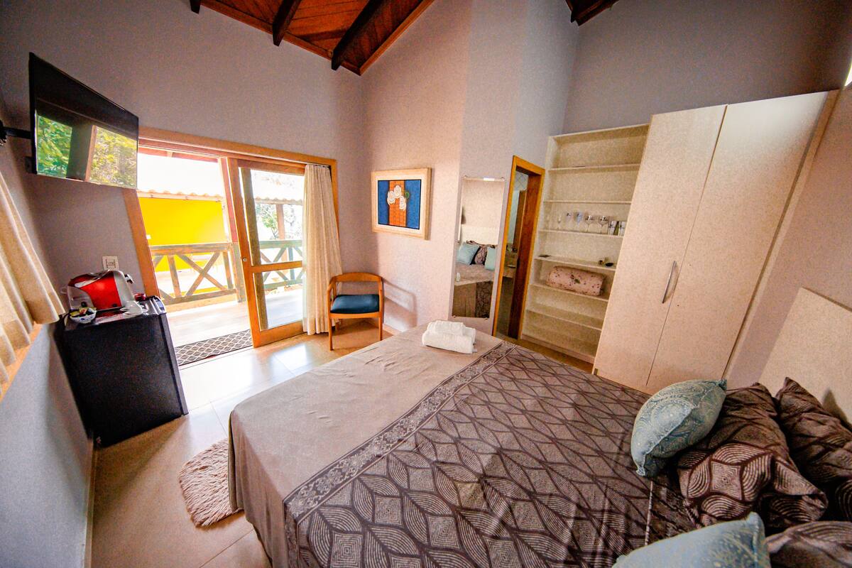 A bedroom with a bed, a wardrobe, a desk with a chair, and a window.