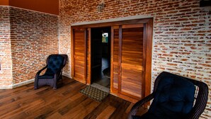 Una habitación con suelo de madera, paredes de ladrillo y dos sillas de mimbre.