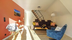 A modern living room with a sofa, a blue armchair, a coffee table, and a staircase.