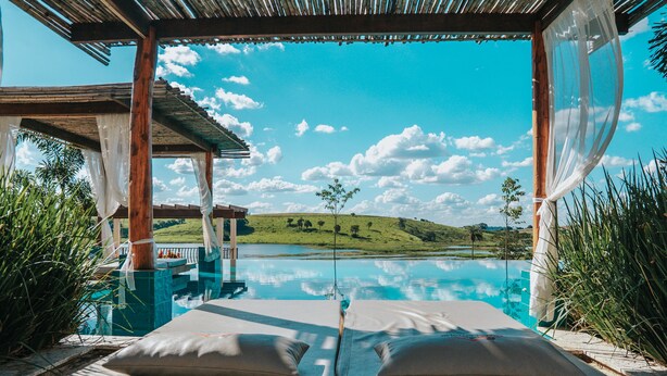 Un área de descanso junto a la piscina con dos sillones acolchados y vistas a un paisaje natural.