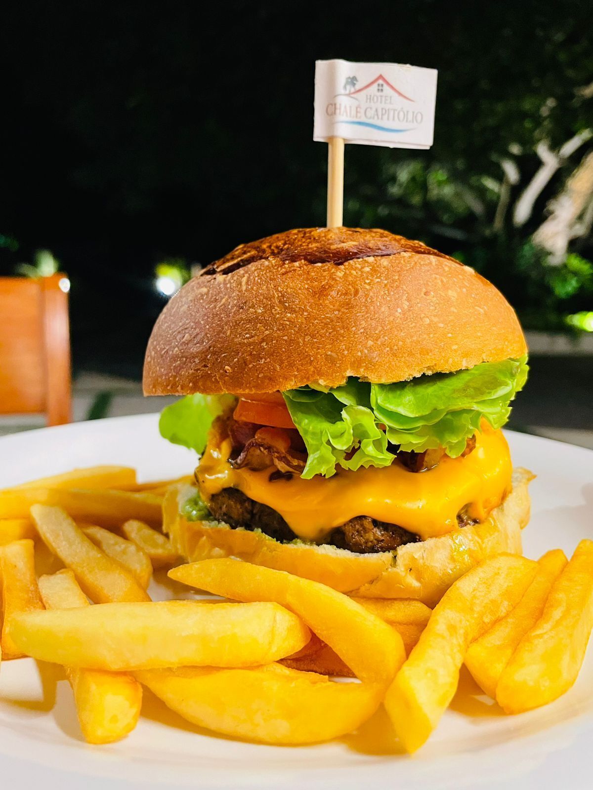 A hamburger with a flag on top, served with French fries.
