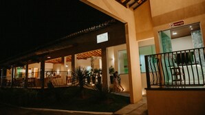 Fachada de hotel con recepción, zona de estar cubierta al aire libre y una escalera que lleva a la entrada.