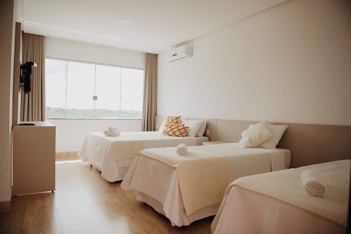 Habitación de hotel con dos camas, un minibar y un ventanal grande con cortinas.