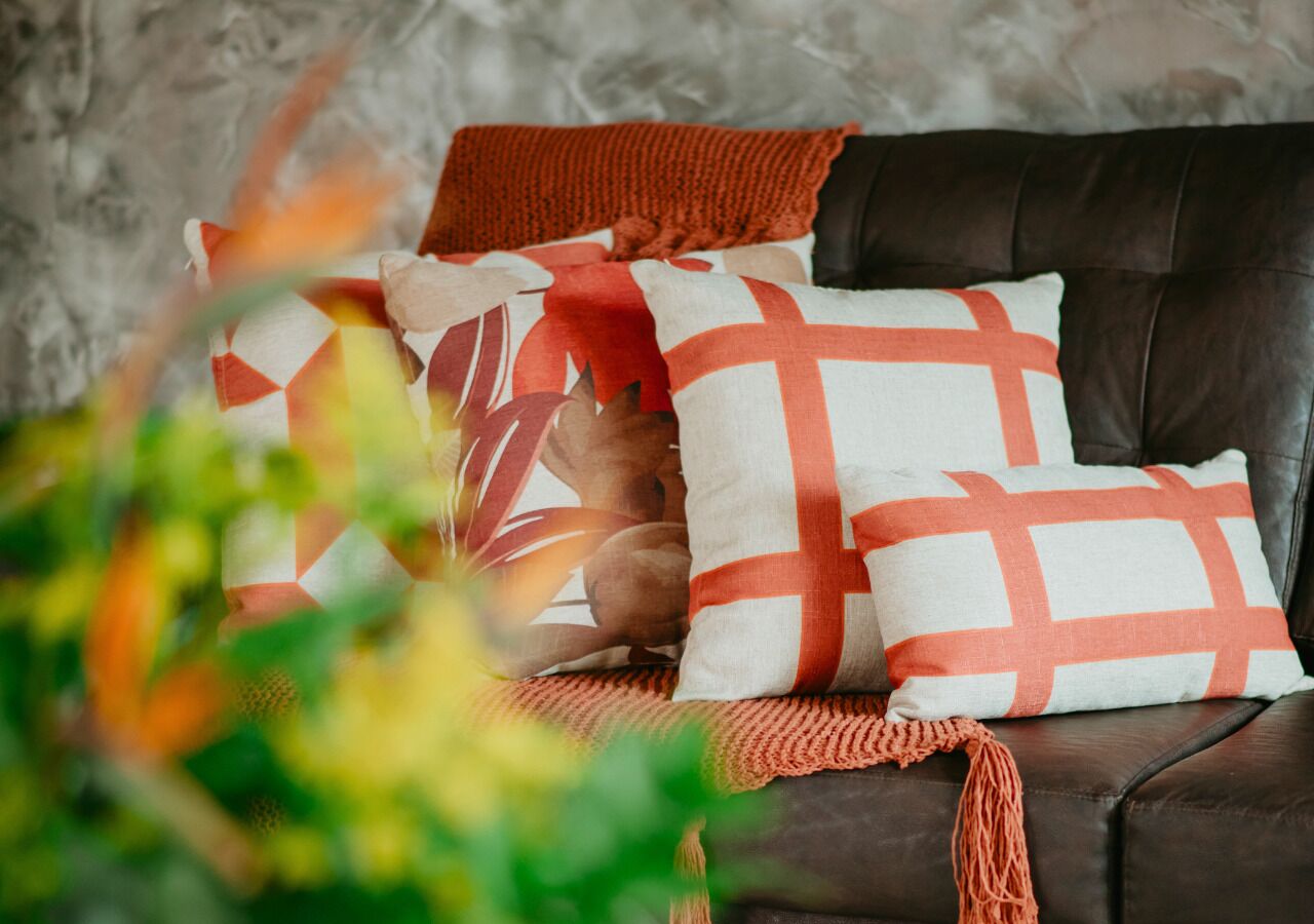 A leather sofa with patterned cushions and a knitted throw.