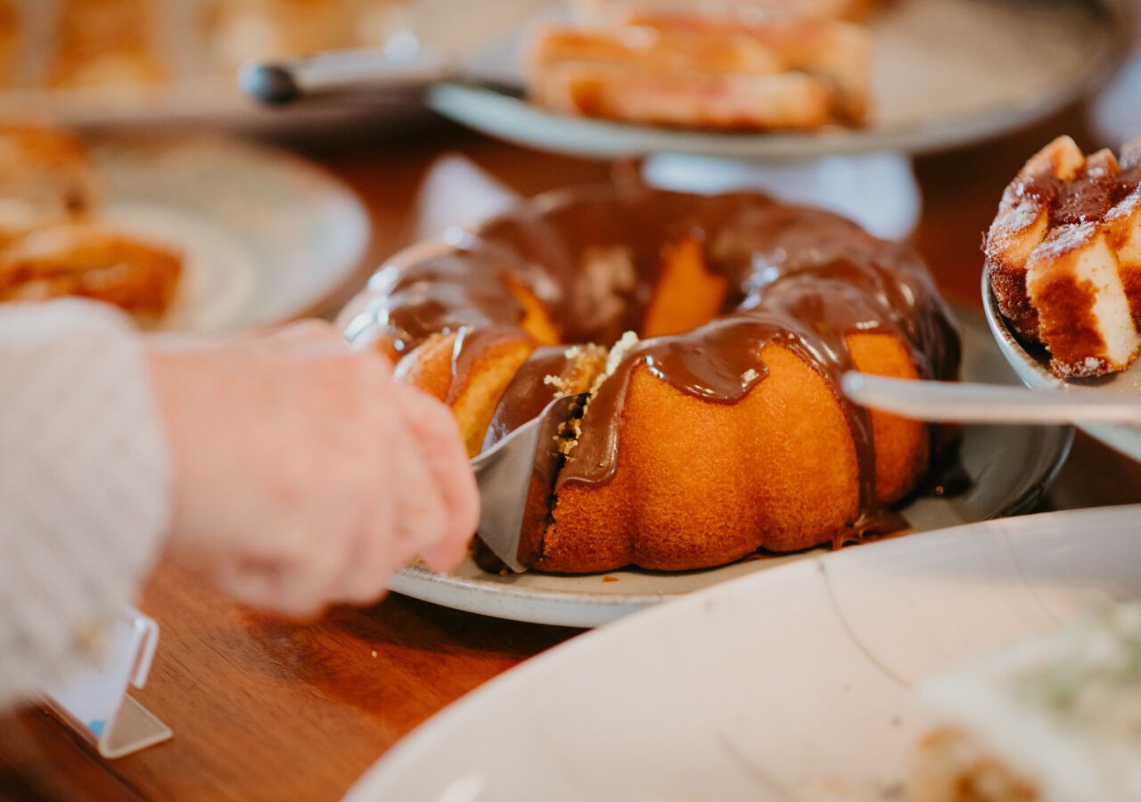 A person cutting a bundt cake with a knife.