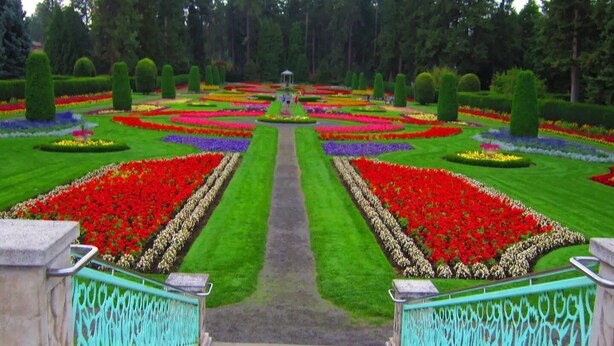 A formal garden with symmetrical flower beds and a central pathway.