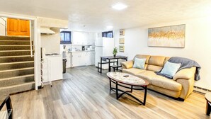 A spacious living area with a sofa, coffee table, and a kitchen in the background.