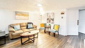 A living room with a beige sofa, two armchairs, a coffee table, and artwork on the walls.