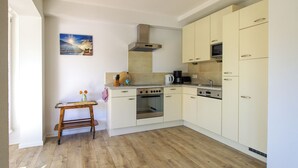 Une cuisine avec un plancher en bois, une cuisinière, un four et des placards.