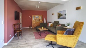 Un salon comprenant un canapé, un fauteuil, un meuble en bois et un téléviseur.