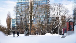 A modern building with multiple floors and large windows, surrounded by bare trees and a snow-covered ground. - Easy Rent Apartments - CRYSTAL (Lublin)