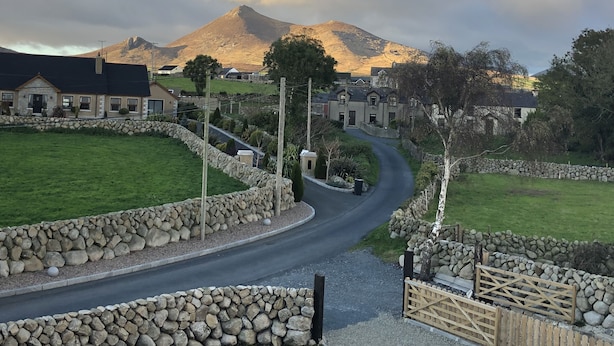 A rural road leading to a stone-walled property with a mountain in the background. - Cosy Cottage at the foot of The Mournes (Ballymartin)
