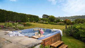 Un jacuzzi con gabinete de madera, una botella de vino y copas sobre una bandeja.