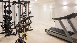 Un gimnasio con cinta de correr, máquinas de pesas y un muro de espejos.