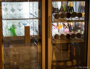 Une vitrine réfrigérée contenant diverses bouteilles d’alcool, notamment du vin et du champagne, ainsi qu’un assortiment de verres à vin.