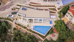 Una casa moderna con una gran piscina, un porche cubierto y un jardín.