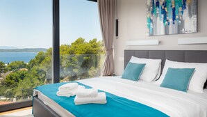 Un dormitorio moderno con una cama grande, vista al mar y un cuadro en la pared.