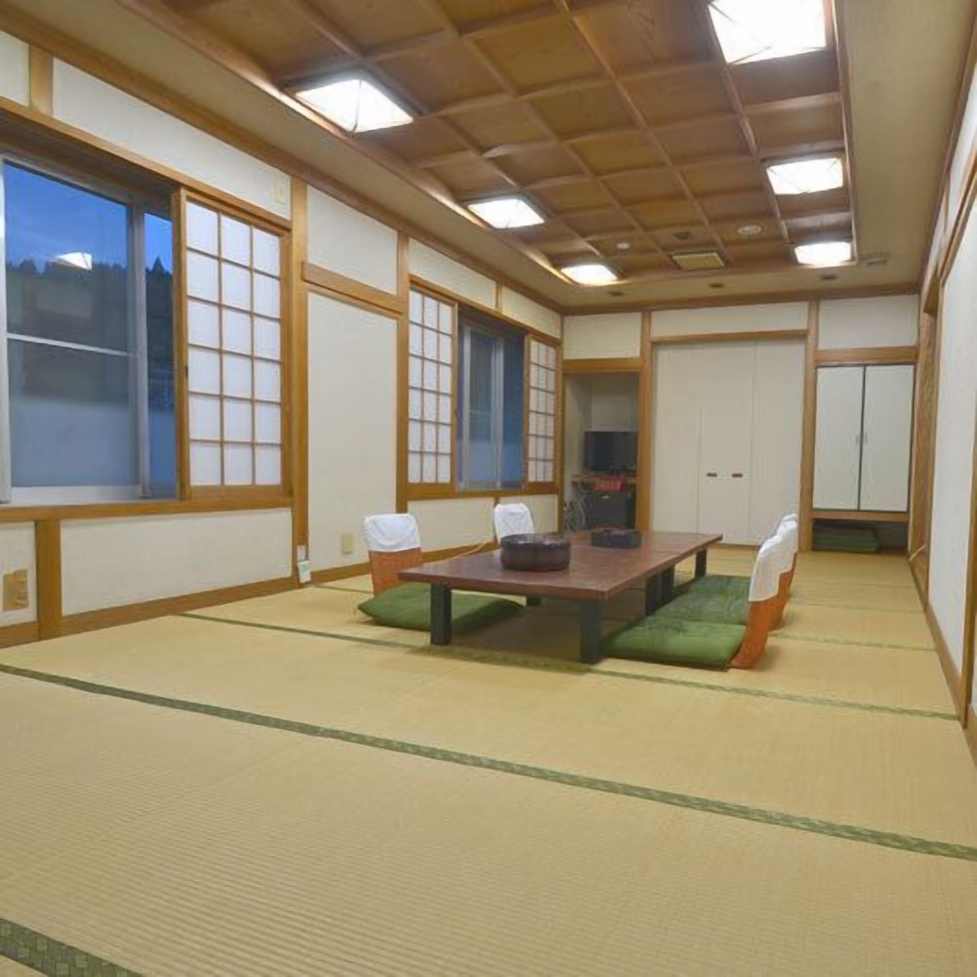 Una habitación japonesa tradicional con suelo de tatami, una mesa baja y puertas correderas.