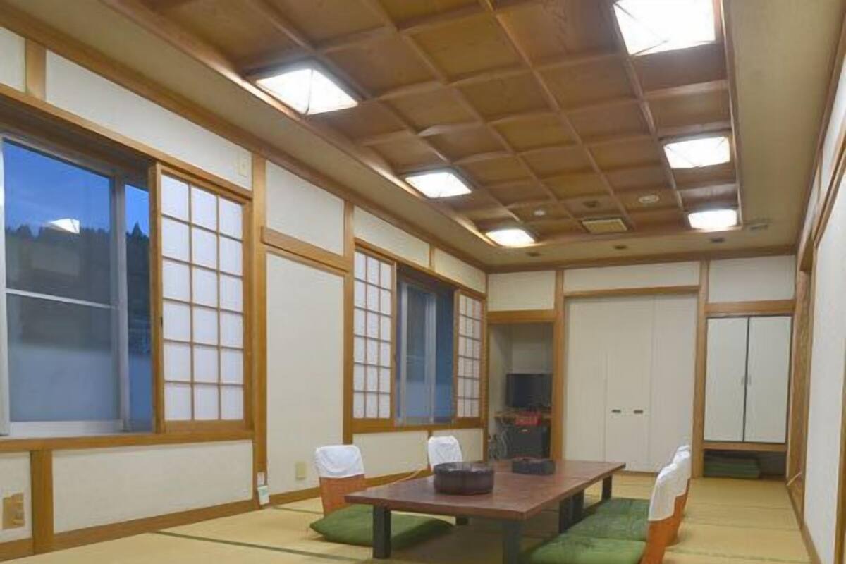 Una habitación japonesa tradicional con suelo de tatami, una mesa baja y puertas correderas.