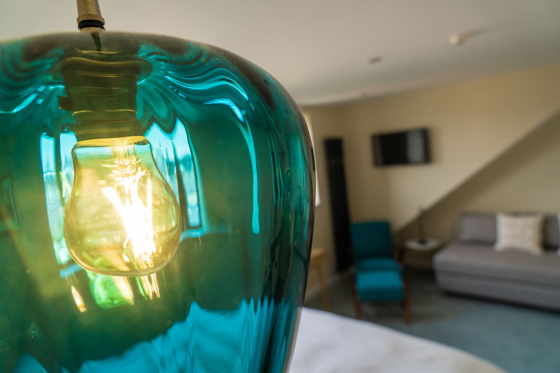 Una habitación con una lámpara color turquesa, una cama, una escalera y un sofá.