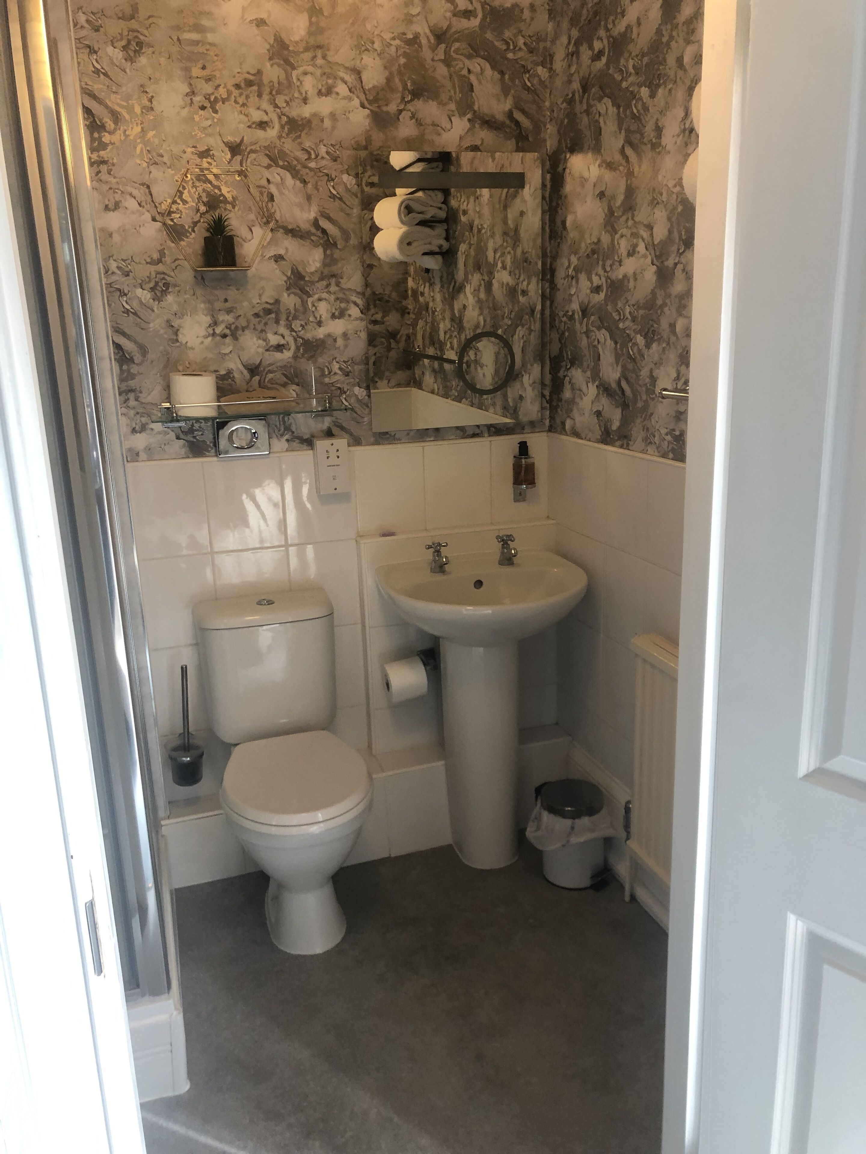 A bathroom with a toilet, sink, and a marble-patterned wall.