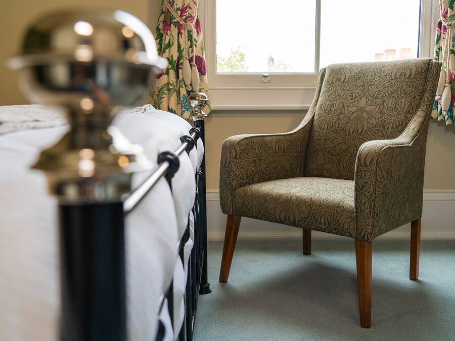 A bedroom with a bed, a chair, and a window with curtains.