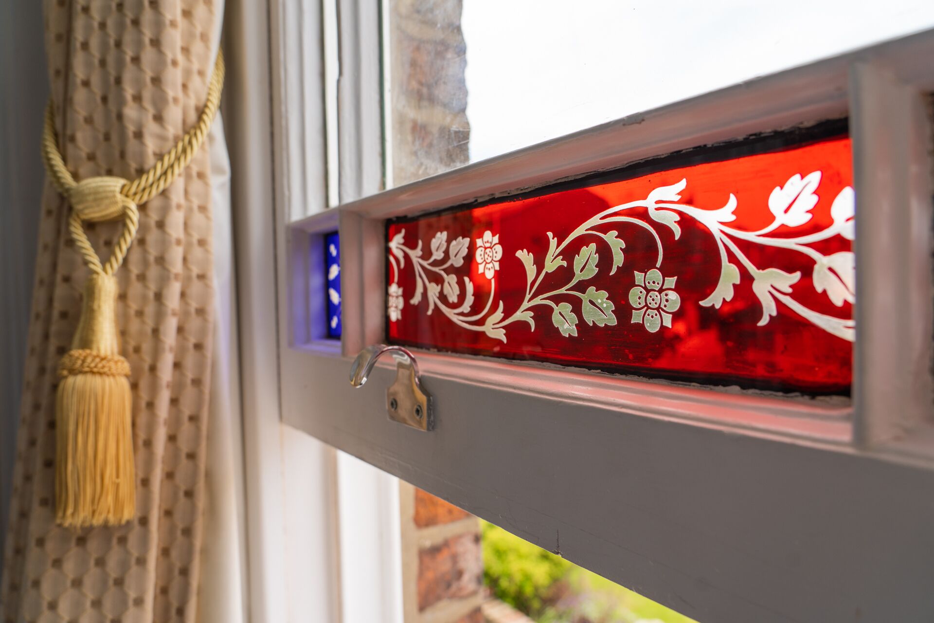 Una ventana con un panel de vidrio decorativo con motivos florales.