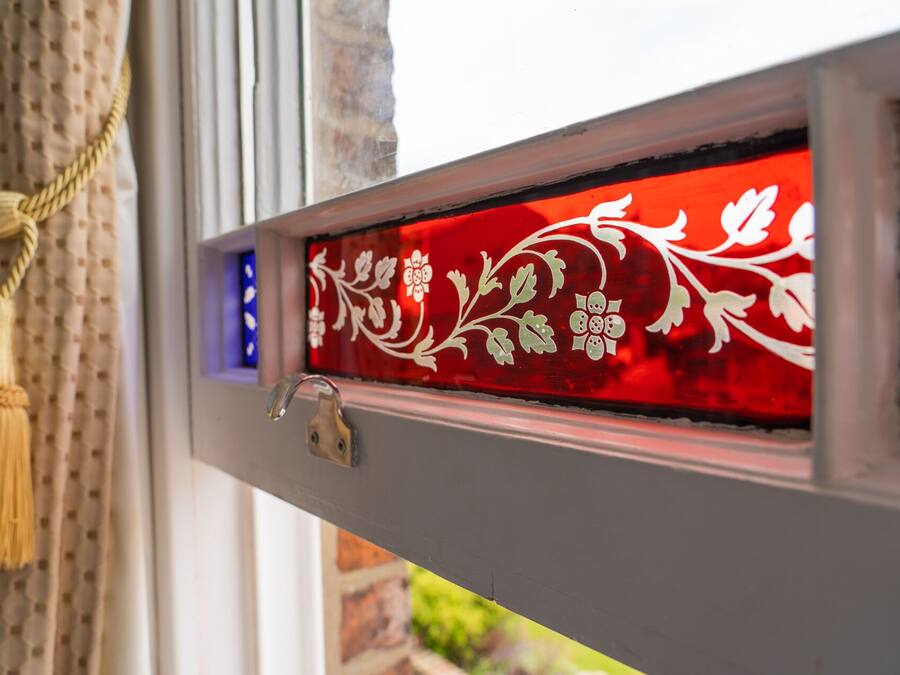 Una ventana con un panel de vidrio decorativo con motivos florales.