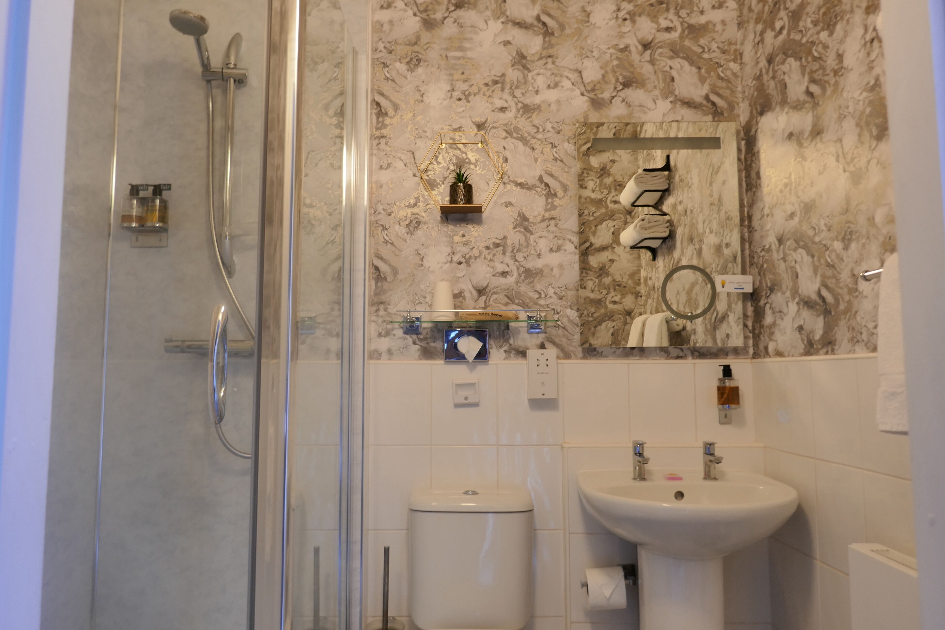 A bathroom with a glass shower enclosure, a toilet, and a sink.