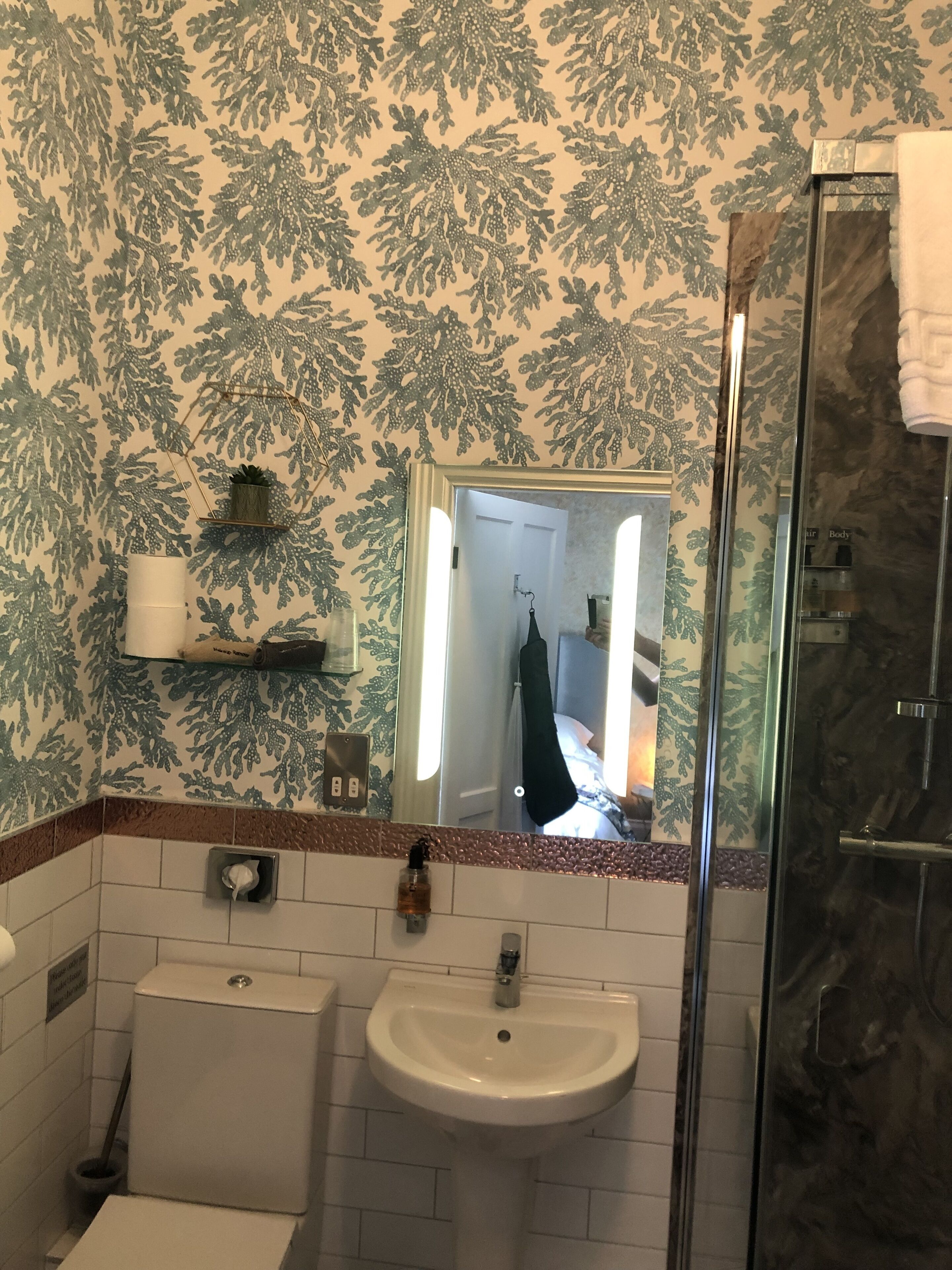 Un baño con lavamanos, inodoro y cabina de ducha de vidrio.