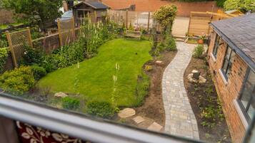 A residential garden with a paved pathway, a lawn, and various plants.