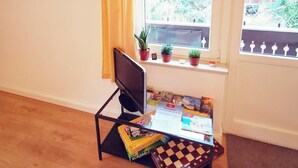 Une pièce avec un plafond en bois, une fenêtre donnant sur des arbres, un bureau avec un ordinateur, un jeu d’échecs et un tableau accroché au mur.