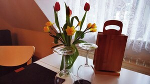 Une table avec un vase de tulipes, deux verres à vin et un panier en bois.