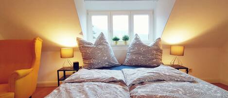 Un dormitorio con una cama, dos lámparas de noche, una ventana y una silla.