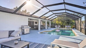 Ein Außenpoolbereich mit überdachter Terrasse, Sitzgelegenheiten und Grill.