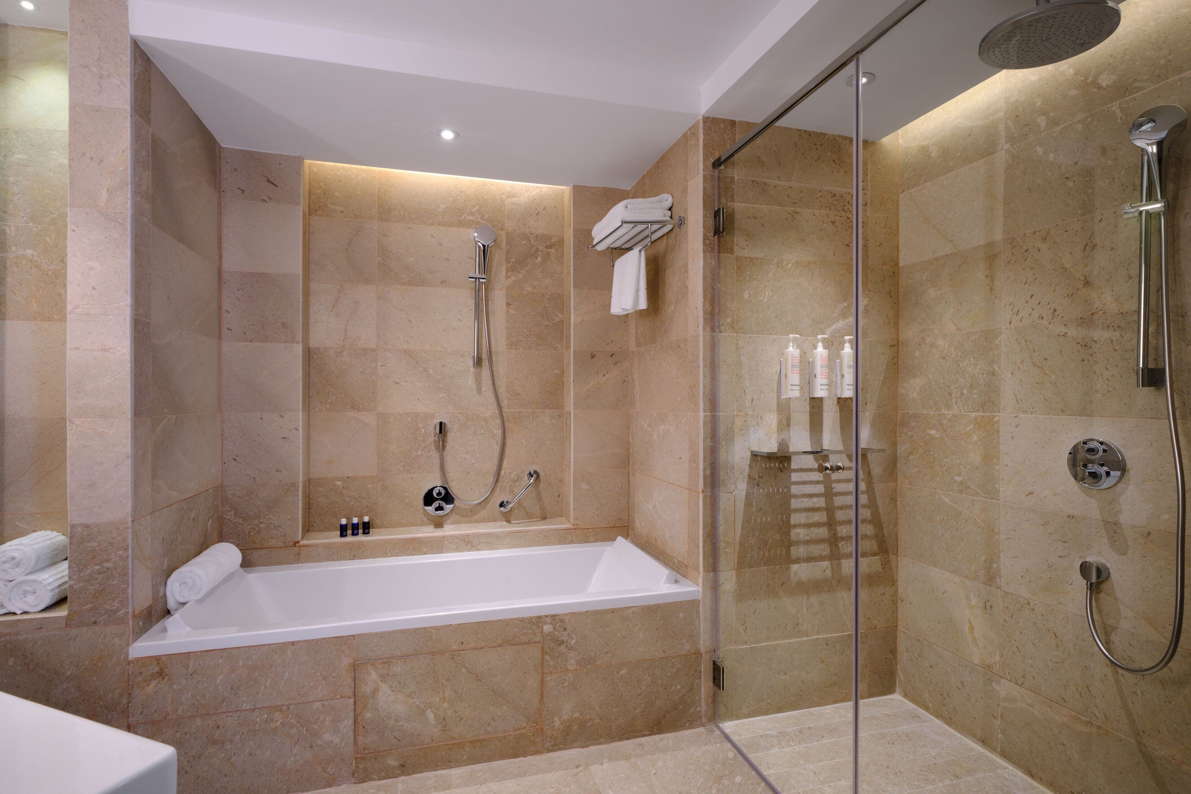 A modern bathroom with a bathtub, shower, and glass-enclosed shower area.
