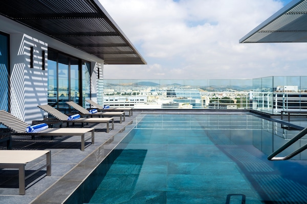 Una piscina al aire libre, sombrillas, sillones reclinables de piscina