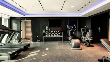 Un gimnasio moderno con cintas de correr, una bicicleta estática y una silla de masaje.