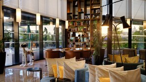 A modern lobby with a large bookshelf, seating area with cushions, and a decorative cat statue. - Tunis Marriott Hotel (Tunis)