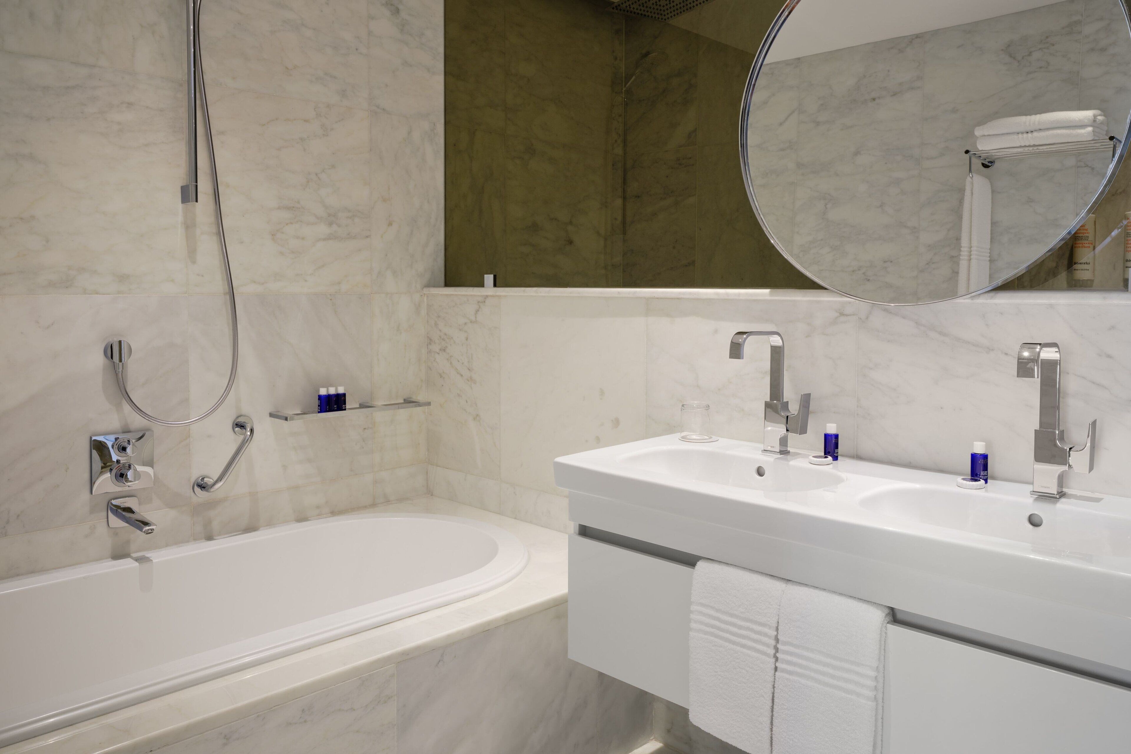 Un baño moderno con una bañera, dos lavamanos y un espejo grande.