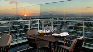 A dining table with chairs and a view of a cityscape at sunset. - Tunis Marriott Hotel (Tunis)