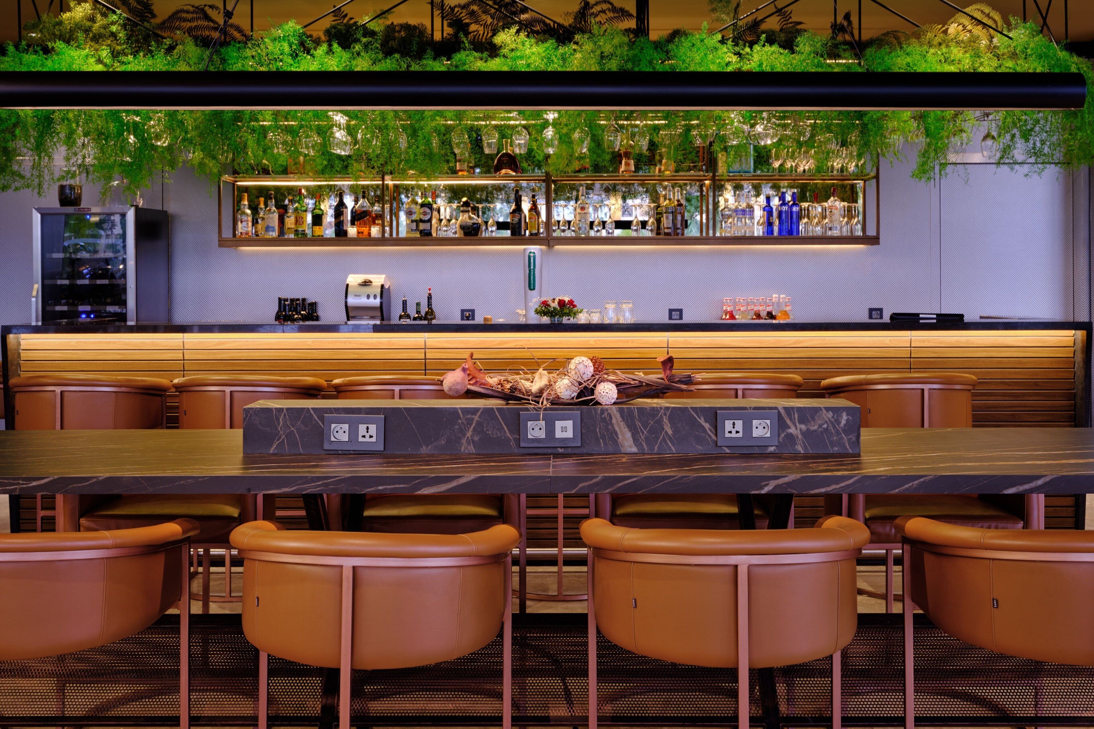 A bar area with a long counter, multiple seating options, and a variety of bottles and glasses on display.