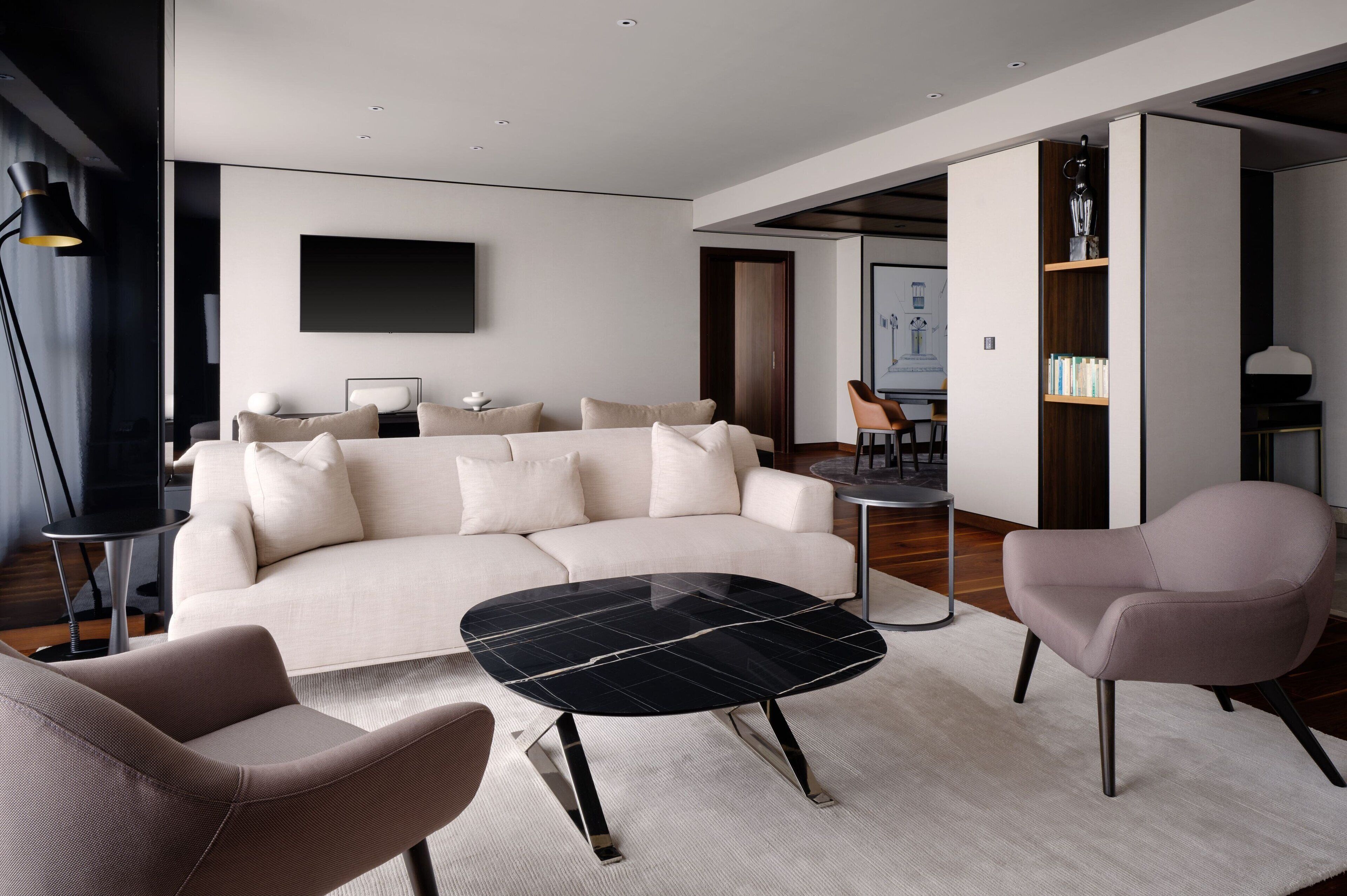 Una sala de estar moderna con un sofá, dos sillones, una mesa de centro y una estantería.