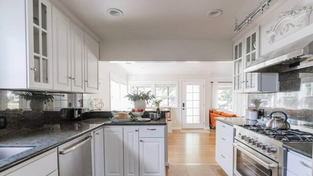 A spacious kitchen with white cabinetry, a central island, and a large stove. - Stargaze your evenings away in the private backyard Hot Tub. (Chico)