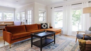 A living room with a sofa, a coffee table, and a patterned rug. - Stargaze your evenings away in the private backyard Hot Tub. (Chico)